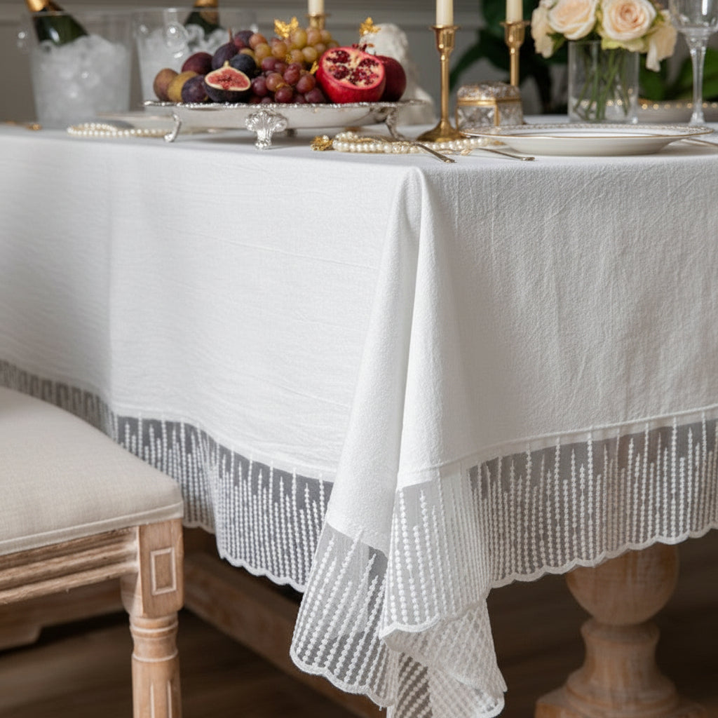 Elegant table setting with a white lace tablecloth, fruit platter, and candles.