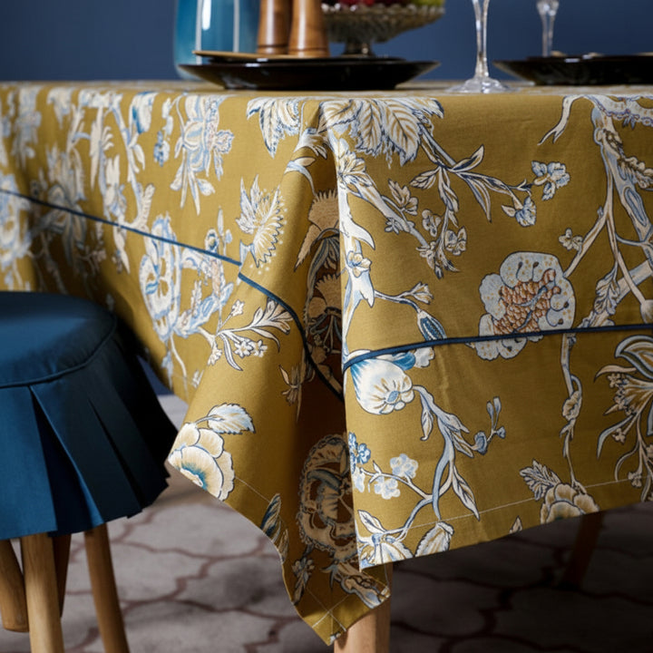 Floral-patterned tablecloth on a dining table with a blue chair and dark surface.