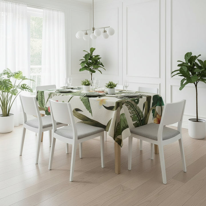 Dining room with a table set for four, featuring a leaf-patterned tablecloth and potted plants.
