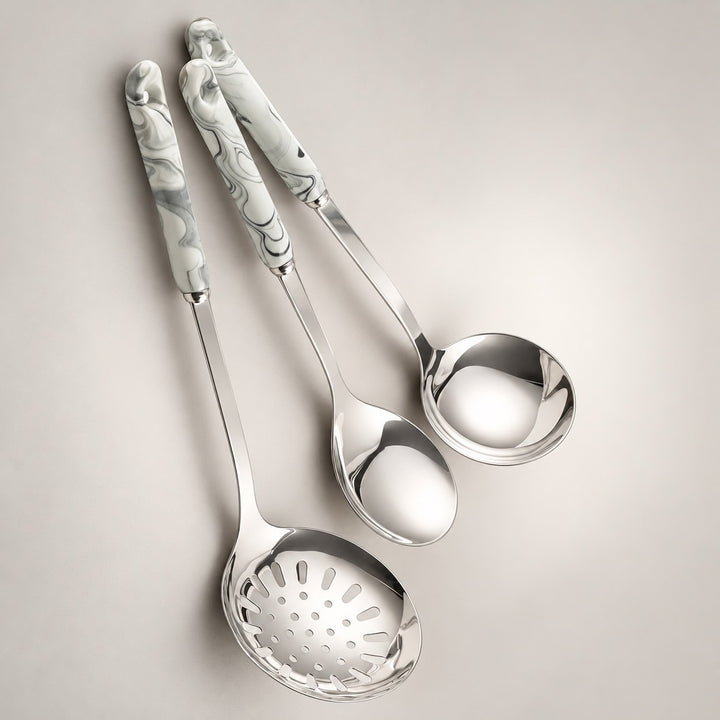 Three stainless steel kitchen serving utensils with grey marbled handles, arranged diagonally on a light grey background.