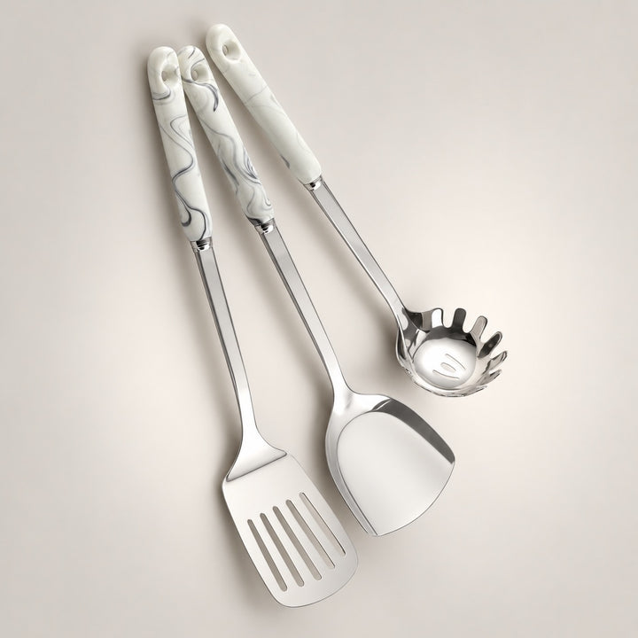Three stainless steel kitchen serving utensils with grey marbled handles, arranged diagonally on a light grey background.
