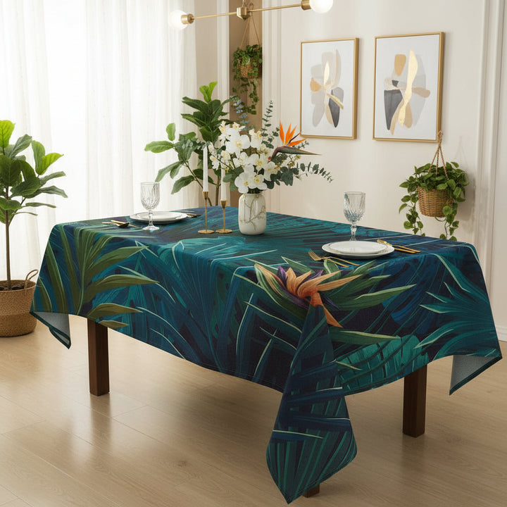 Dining table with a tropical leaf patterned tablecloth, set for a meal.