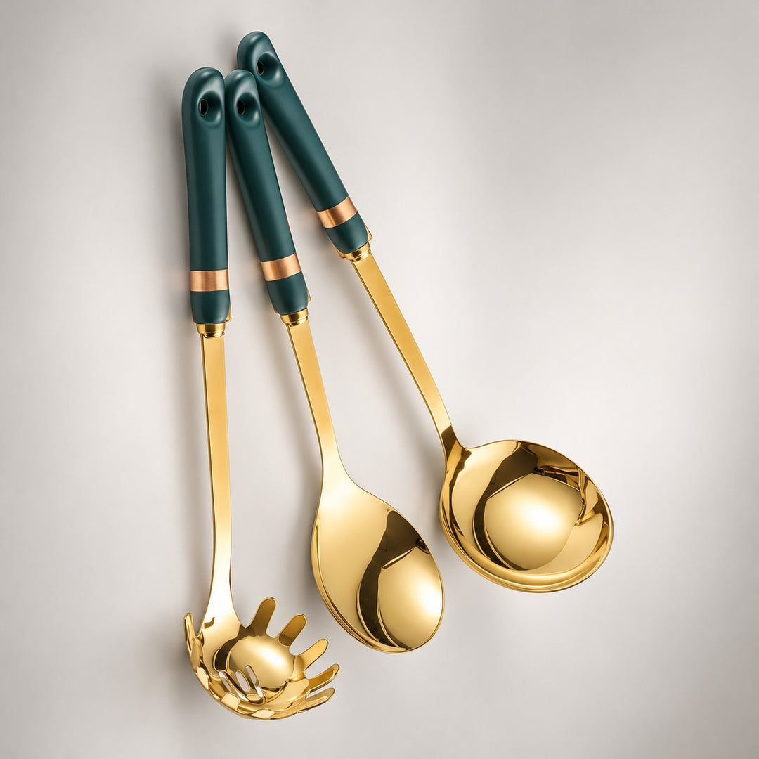 Three gold kitchen utensils with dark teal handles and rose gold bands, including a pasta server, spoon, and ladle, arranged diagonally on a light gray background.