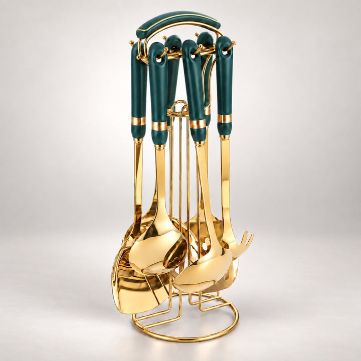 A set of six kitchen utensils with dark green handles and shiny gold metal bodies, displayed on a matching gold stand against a light gray studio background.