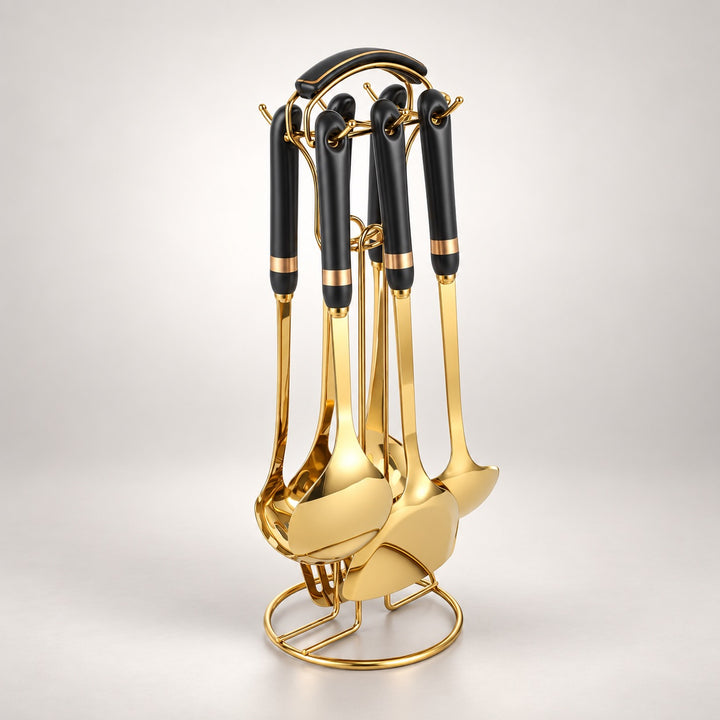 A set of six kitchen utensils with black handles and shiny gold metal bodies, displayed on a matching gold stand against a light gray studio background.