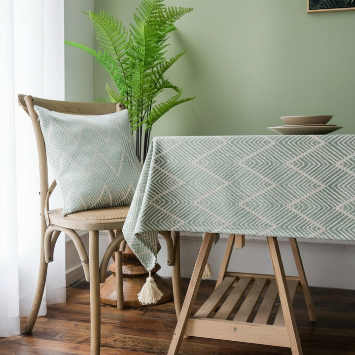 Dining room with a wooden table, a Green geometric-patterned tablecloth, a chair, and decorative elements.