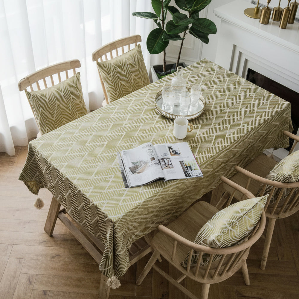 Dining table with a patterned tablecloth, chairs, and a magazine on a wooden floor.