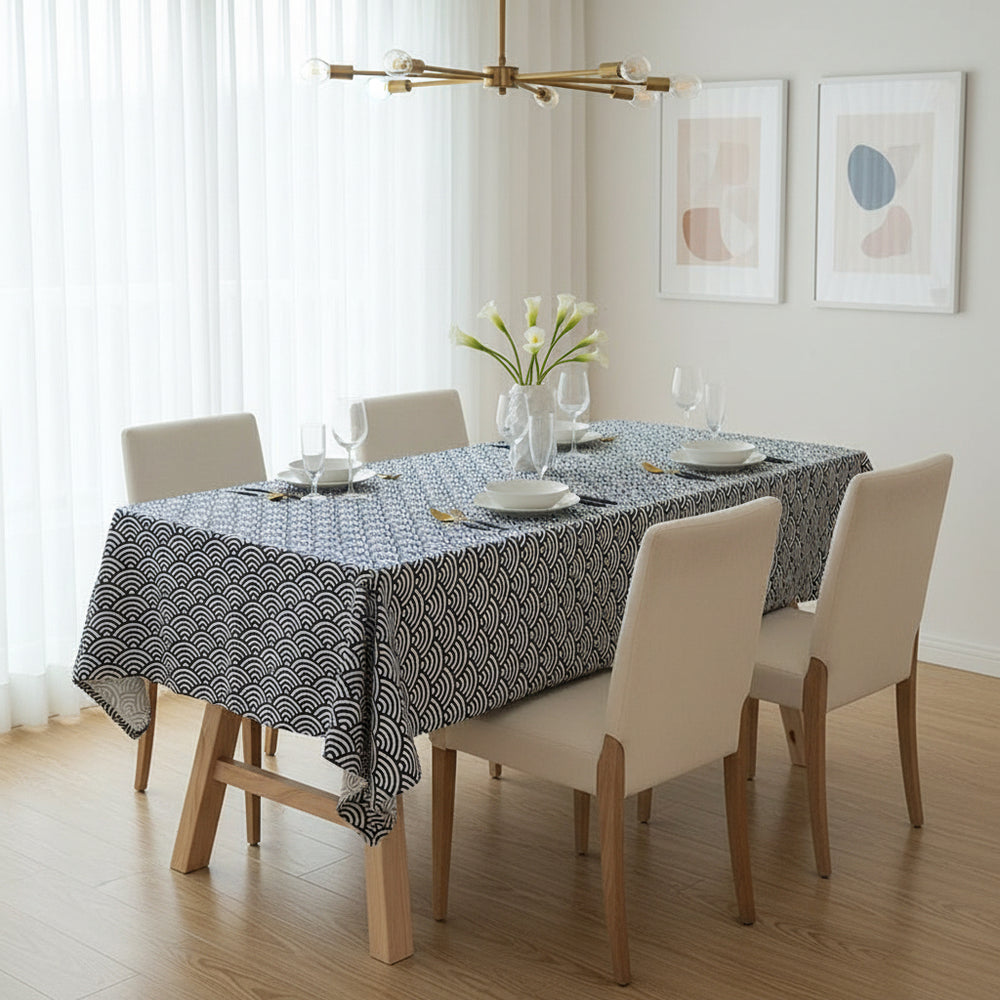 Dining room with a table set for four, featuring a patterned tablecloth and white chairs.
