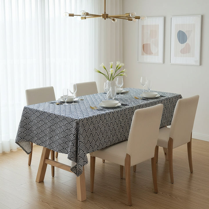 Dining room with a table set for four, featuring a patterned tablecloth and white chairs.