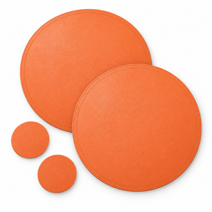 Two round orange faux-leather placemats and two round matching coasters, arranged on a clean white background.