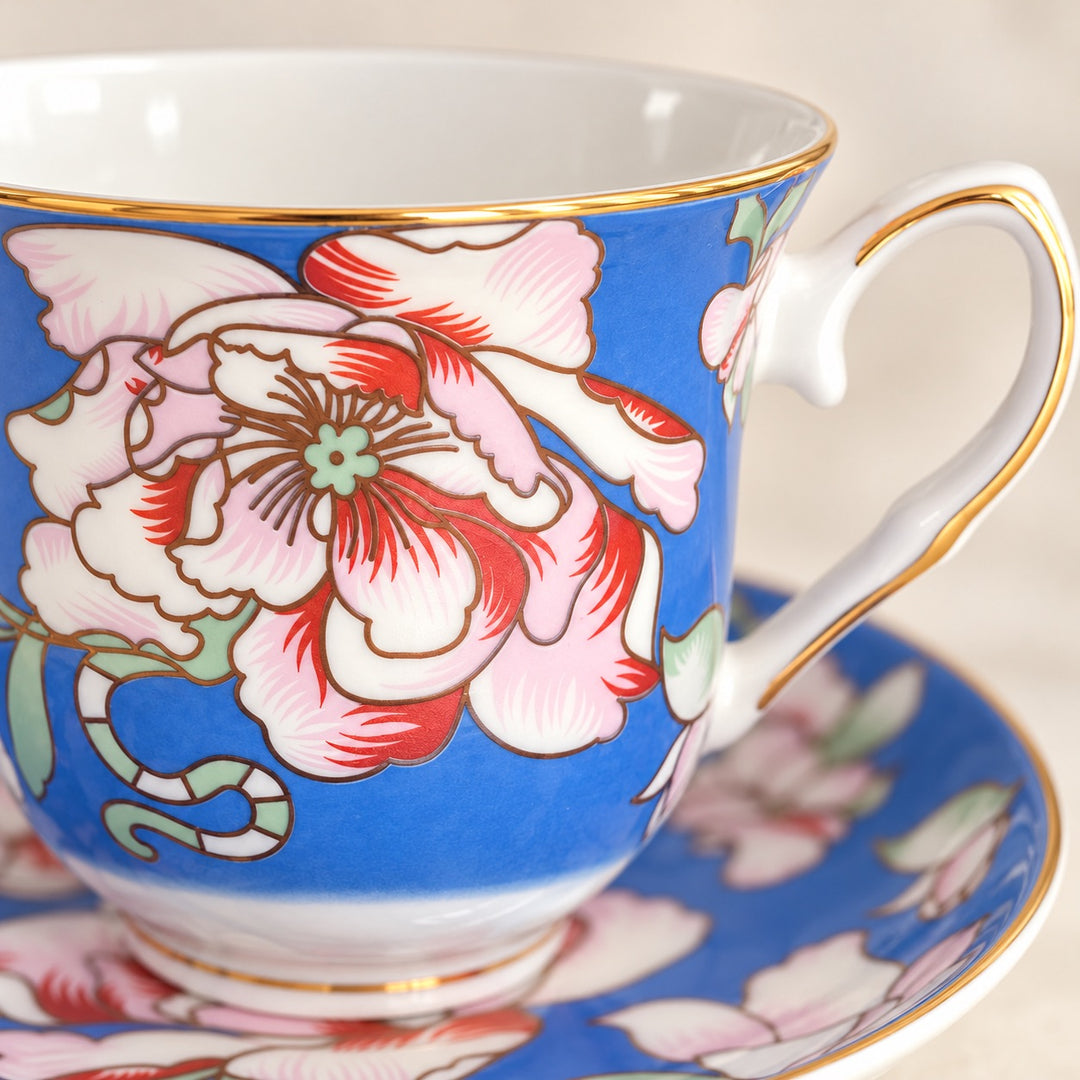 Close-up of a Rosewood Garden teacup showing the floral pattern, gold rim and matching blue saucer