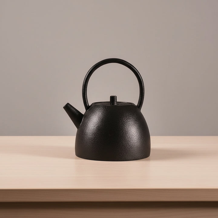 Black teapot on a wooden surface with a neutral background