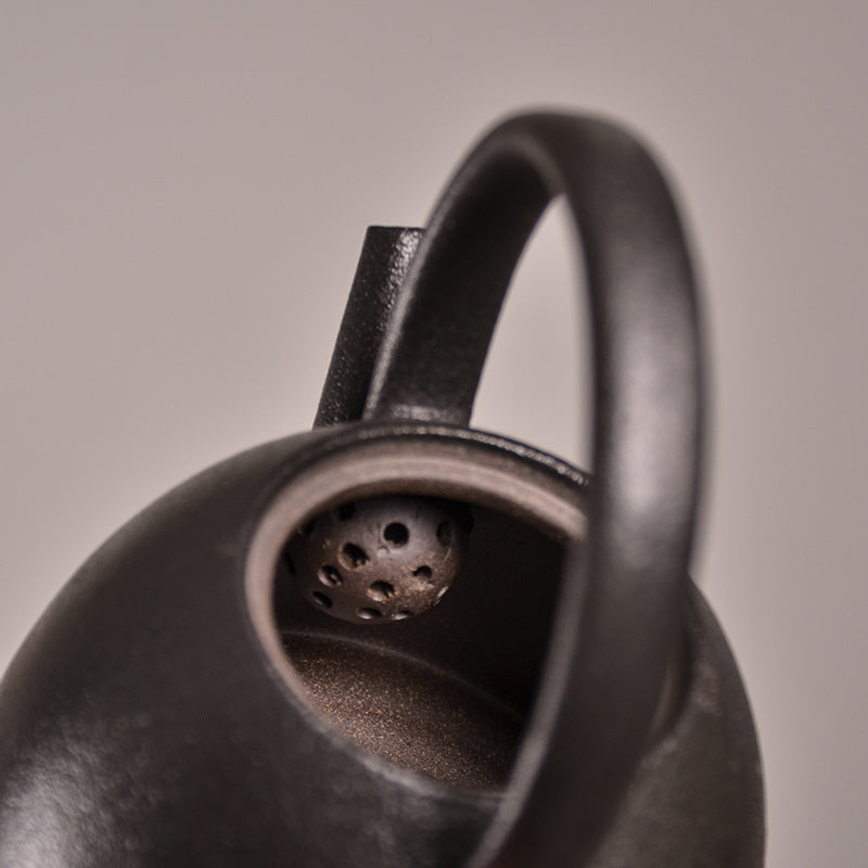 Close-up of a black Stoneware teapot with a handle on a neutral background