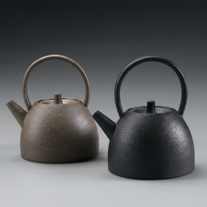 Two Stoneware teapots, one brown and one black, on a grey background.