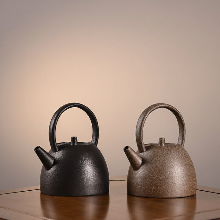 Two Stoneware teapots, one black and one brown, on a reflective surface with a neutral background.