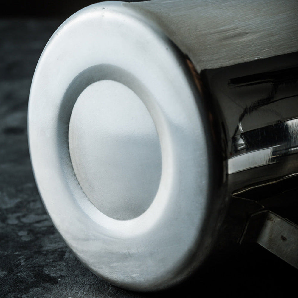 Close-up of a Stainless steel teapot bottom showing a circular component on a dark background