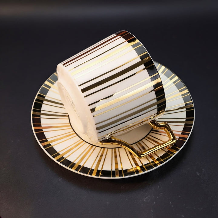 Angled view of Tuxedo Gilt teacup and saucer highlighting 22k gold striping and black band