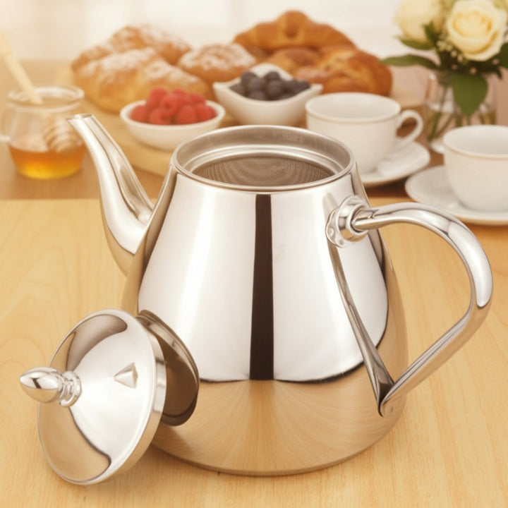 Silver teapot on a wooden table with breakfast items in the background