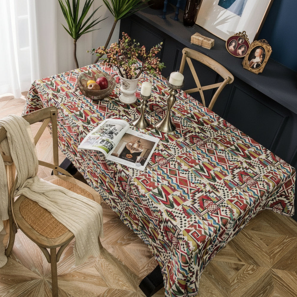 Dining table with a patterned tablecloth, chairs, and decorative items in a room.